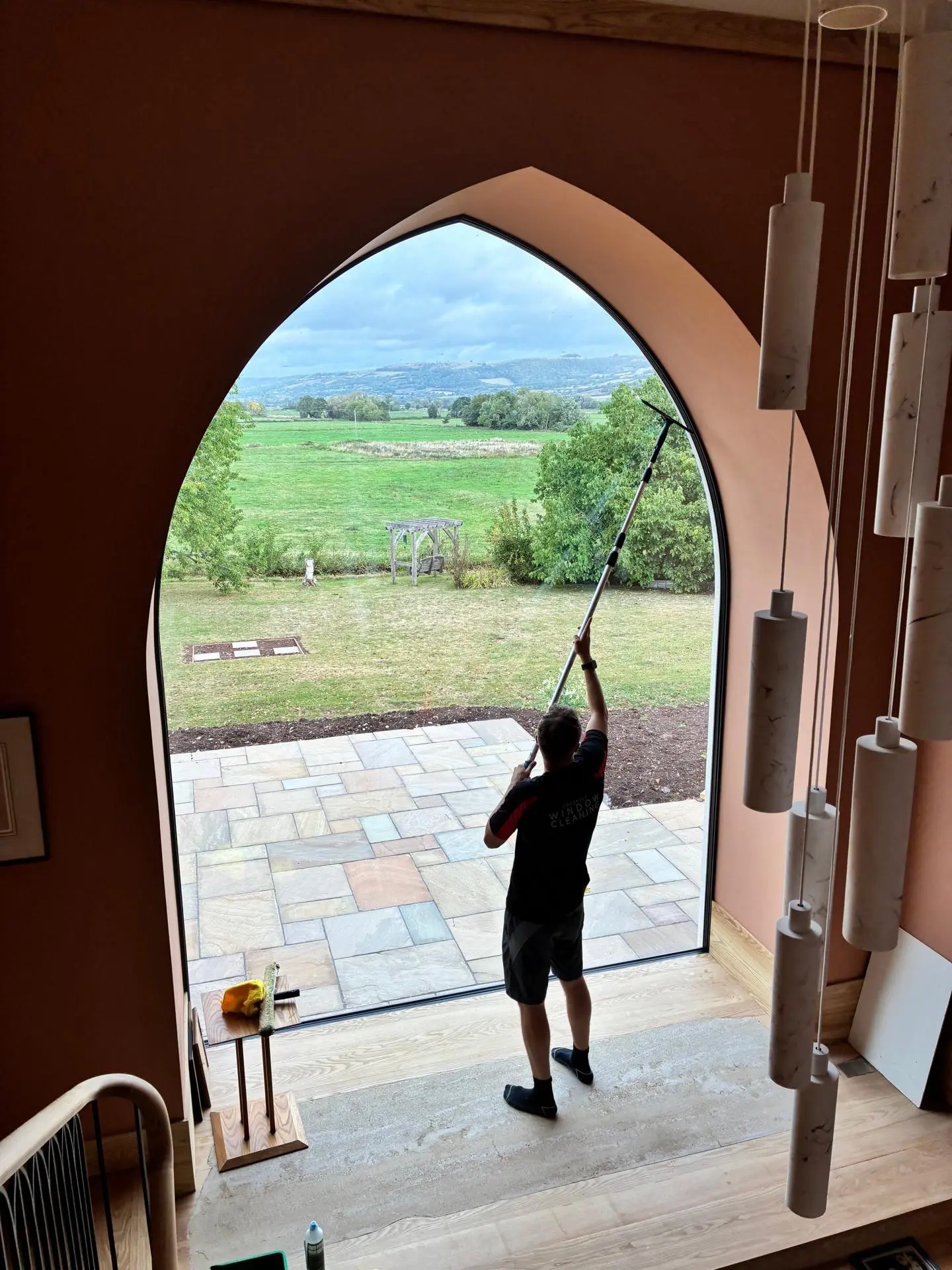 Somerset Window Cleaning technician cleaning the inside of a tall arched window with a pole