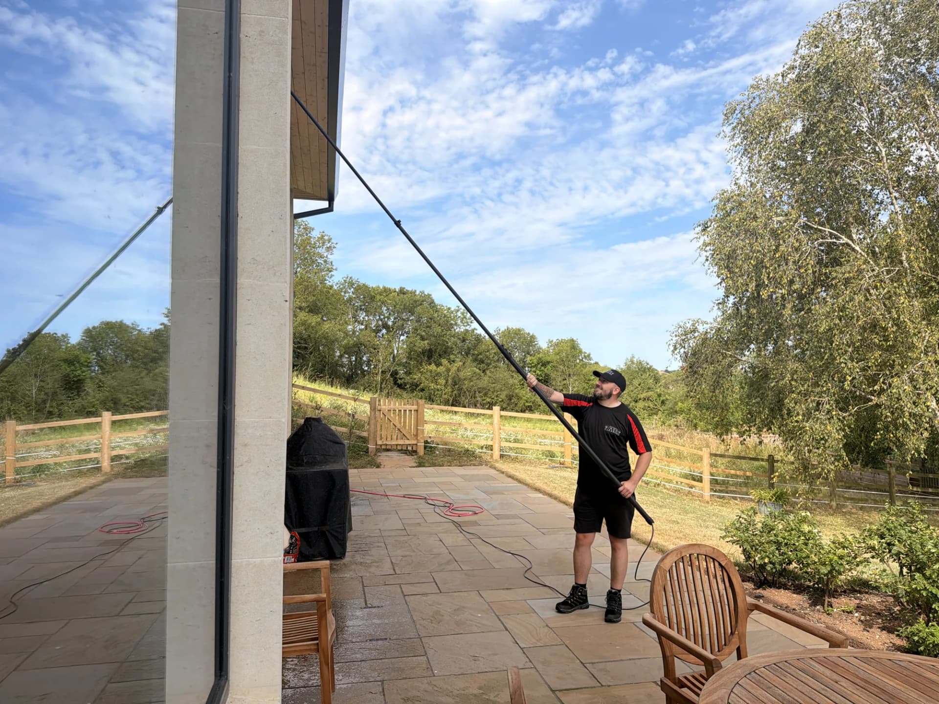 A Somerset Window Cleaning technician reaching first-floor windows from the ground with a reach-and-wash pole