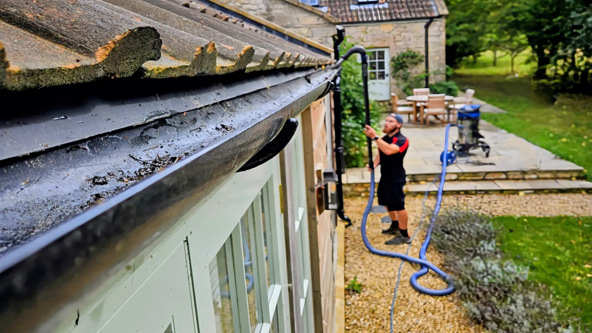 Somerset Window Cleaning technician clearing a gutter with a vacuum pole from the ground