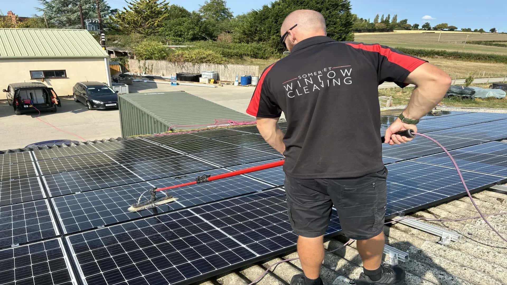 Technician cleaning roof-mounted solar panels with deionised water system